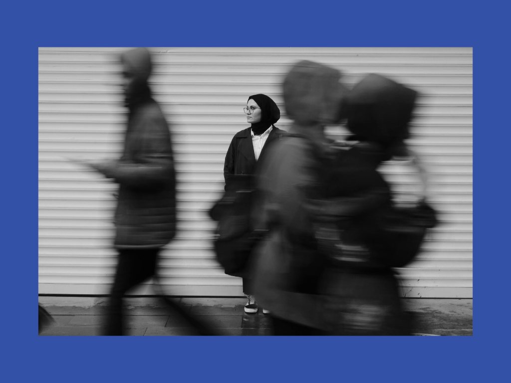 A woman standing still as people rush past her