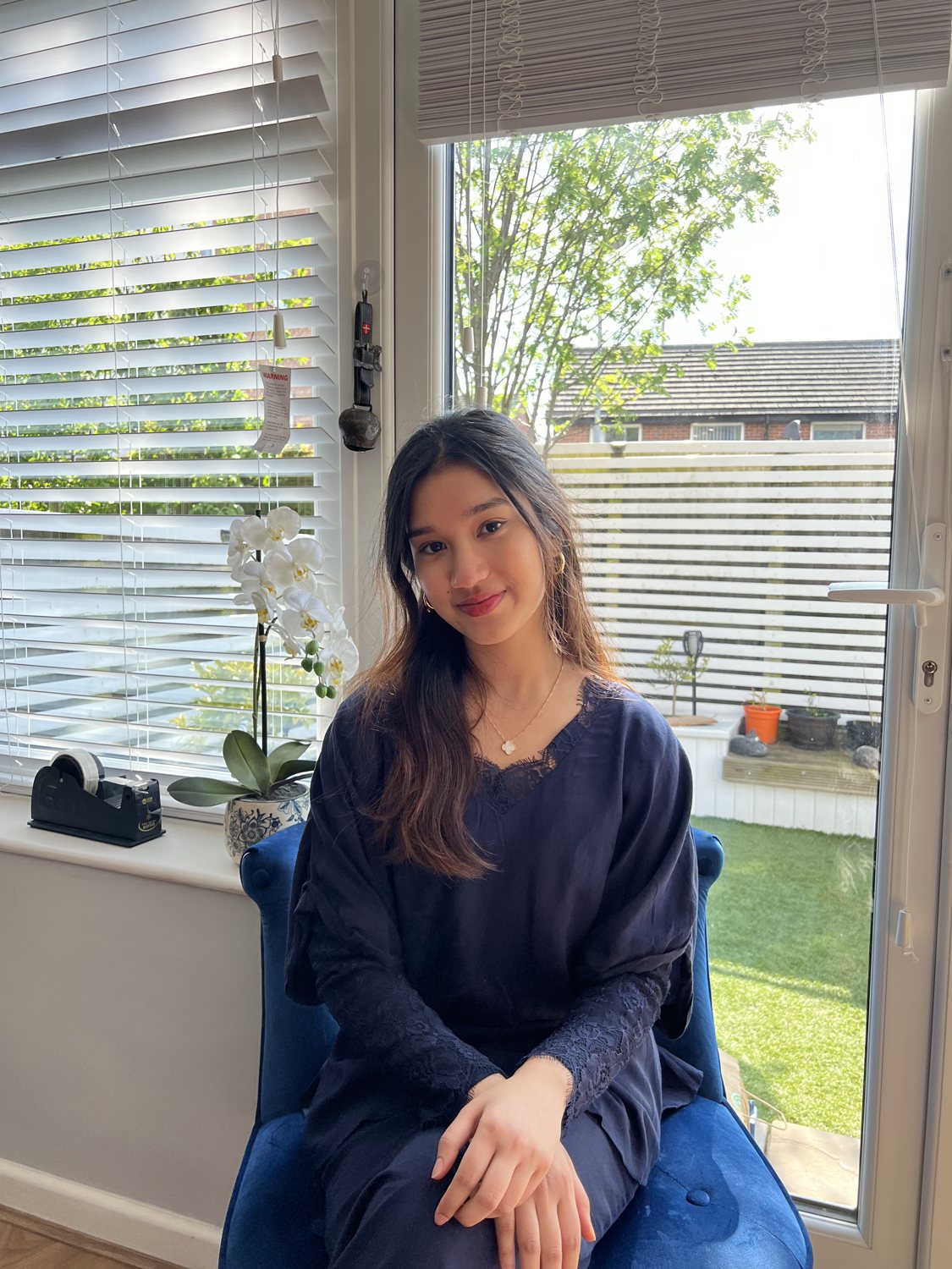Puteri Adriana, smiling, seated by a sunny window